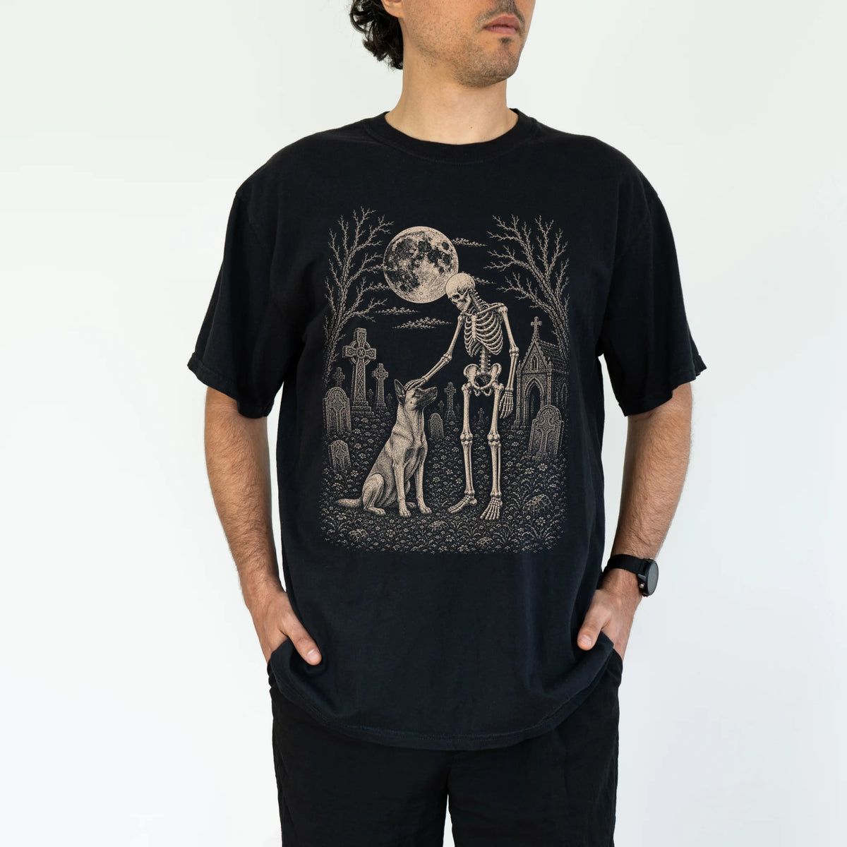 Model wearing a Black Comfort Colors® T-shirt showing Belgian Malinois sharing a quiet cemetery moment with a friendly skelet
