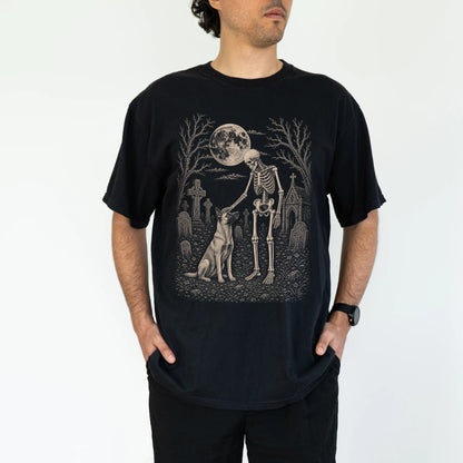 Model wearing a Black Comfort Colors® T-shirt showing Belgian Malinois sharing a quiet cemetery moment with a friendly skelet