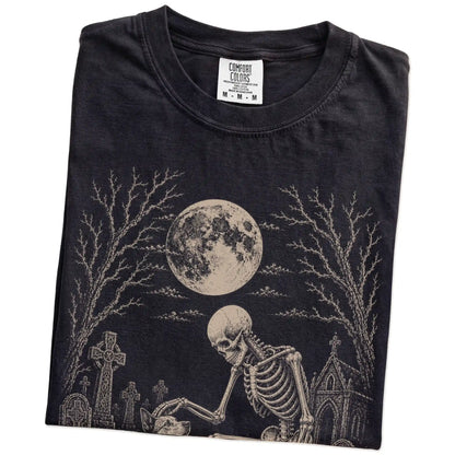 Folded Black Comfort Colors® T-shirt showing Blue Heeler sharing a quiet cemetery moment with a friendly skeleton