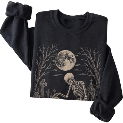 Folded Black sweatshirt with a skeleton petting a Blue Heeler in a graveyard