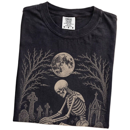 Folded Black Comfort Colors® T-shirt showing Bulldog sharing a quiet cemetery moment with a friendly skeleton