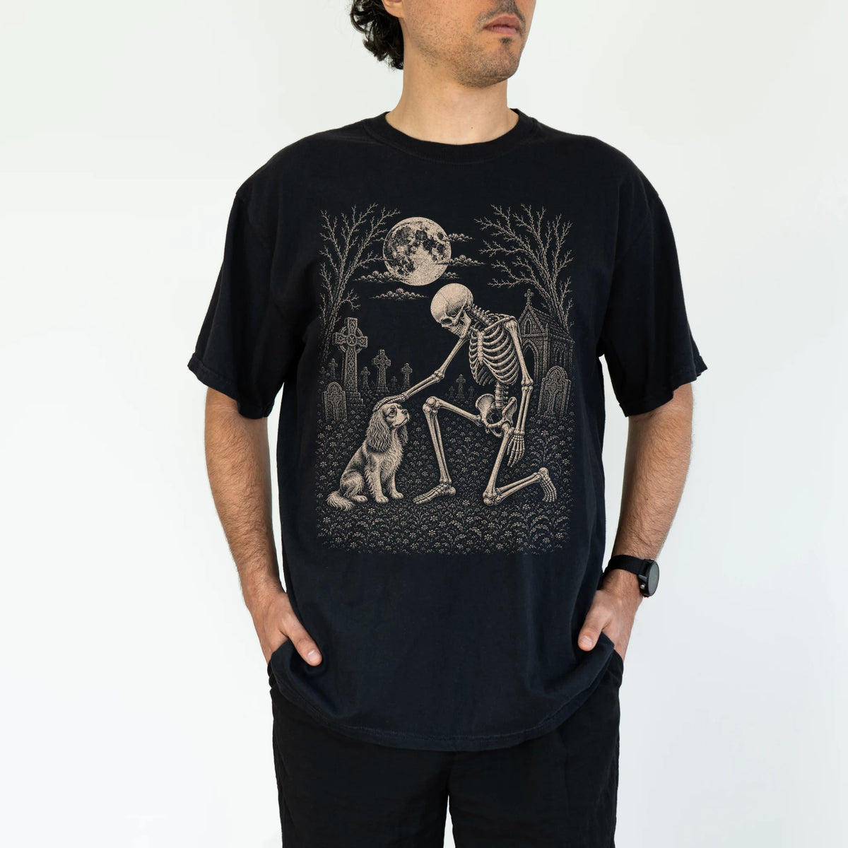 Model wearing a Black Comfort Colors® T-shirt showing Cavalier King Charles Spaniel sharing a quiet cemetery moment with a fr