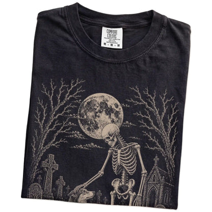Folded Black Comfort Colors® T-shirt showing Collie sharing a quiet cemetery moment with a friendly skeleton