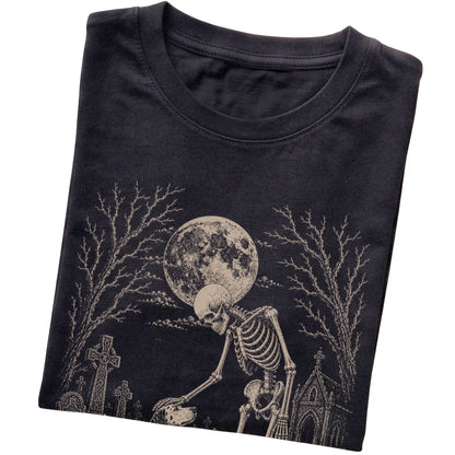 Folded Black T-shirt with a skeleton petting a Dalmatian in a graveyard