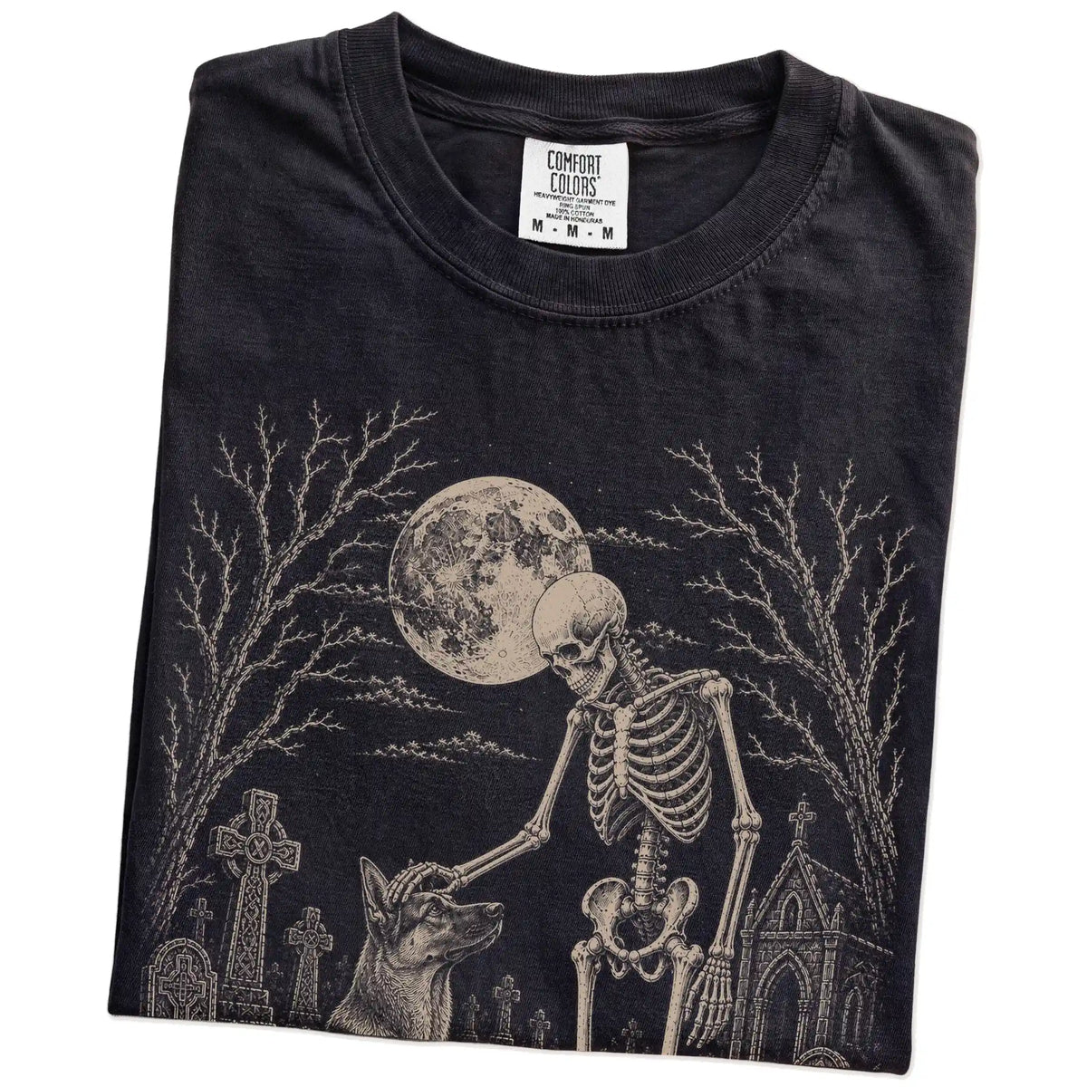 Folded Black Comfort Colors® T-shirt showing German Shepherd sharing a quiet cemetery moment with a friendly skeleton