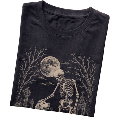 Folded Black T-shirt with a skeleton petting a Golden Retriever in a graveyard