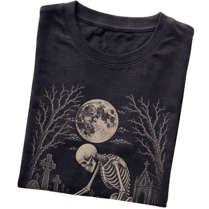 Folded Black T-shirt with a skeleton petting a Jack Russell in a graveyard