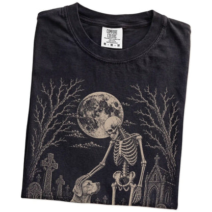 Folded Black Comfort Colors® T-shirt showing Labrador Retriever sharing a quiet cemetery moment with a friendly skeleton