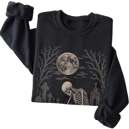 Folded Black sweatshirt with a skeleton petting a Maltese in a graveyard