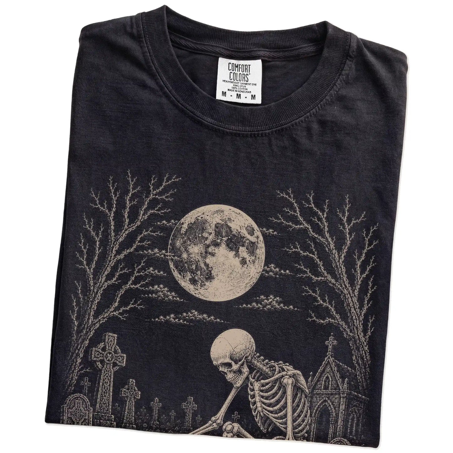 Folded Black Comfort Colors® T-shirt showing Pomeranian sharing a quiet cemetery moment with a friendly skeleton