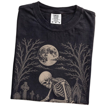 Folded Black Comfort Colors® T-shirt showing Pug sharing a quiet cemetery moment with a friendly skeleton