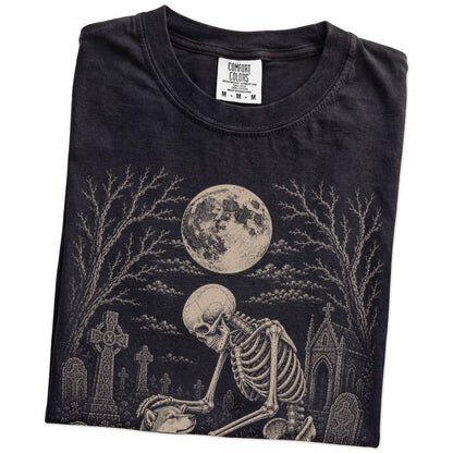Folded Black Comfort Colors® T-shirt showing Shiba Inu sharing a quiet cemetery moment with a friendly skeleton