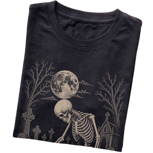 Folded Black T-shirt with a skeleton petting a Shih Tzu in a graveyard