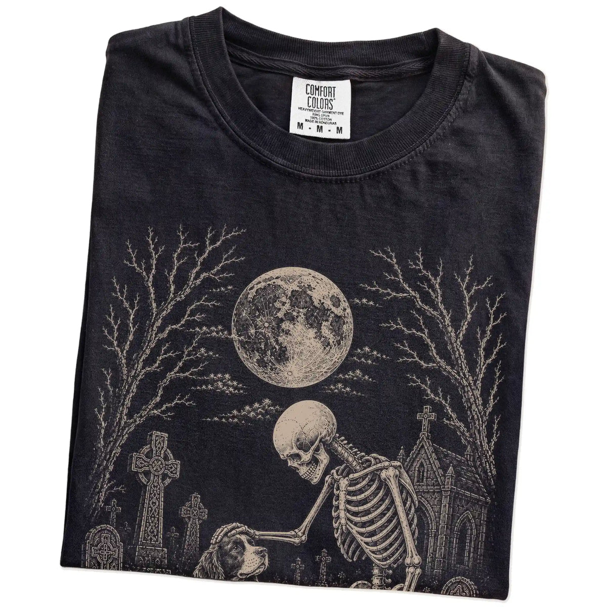 Folded Black Comfort Colors® T-shirt showing Springer Spaniel sharing a quiet cemetery moment with a friendly skeleton