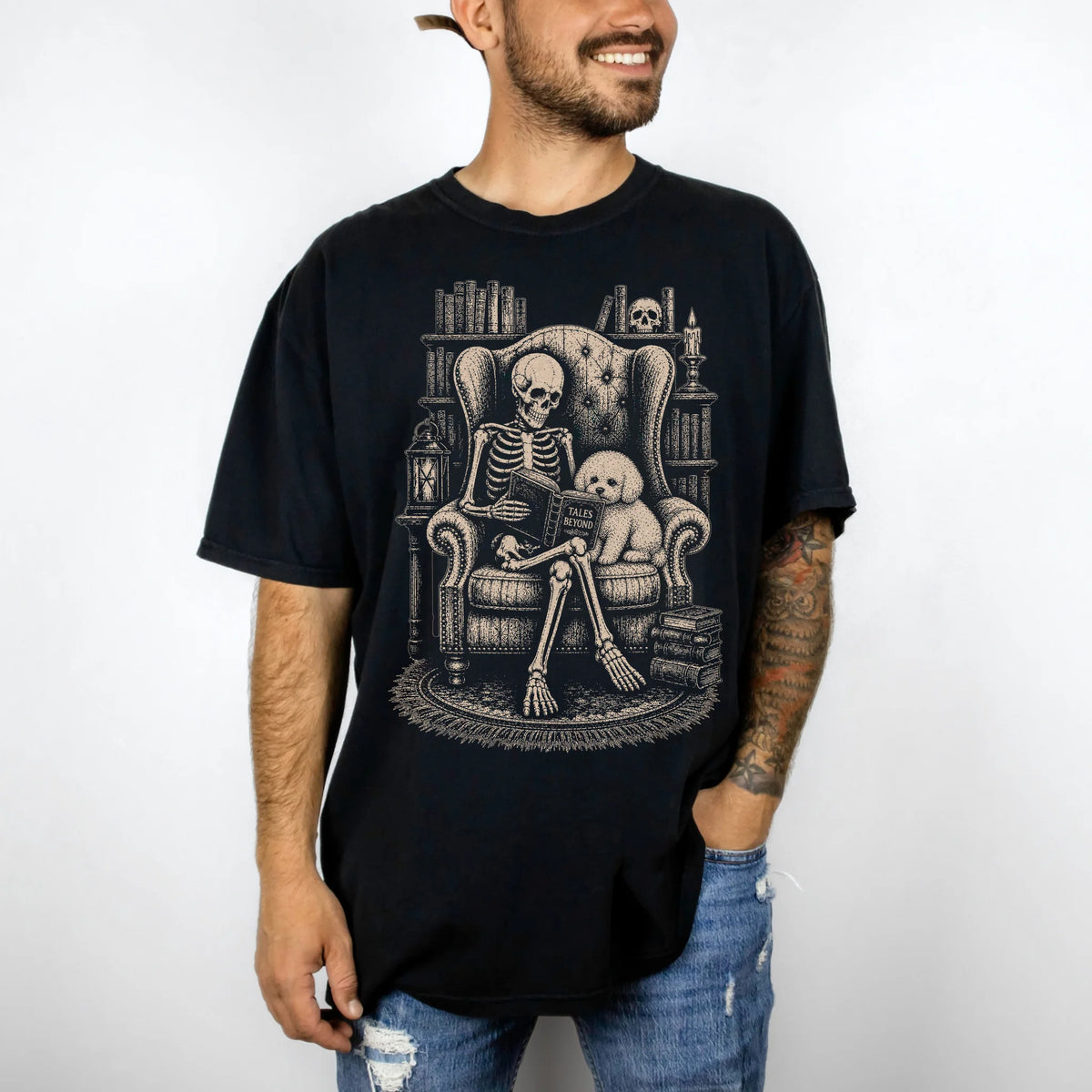 Model wearing a Black Comfort Colors® T-shirt showing skeleton reading in a library beside a Bichon Frise