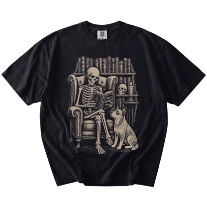 Skeleton reading in a library beside a Blue Heeler on a Black Comfort Colors® T-shirt
