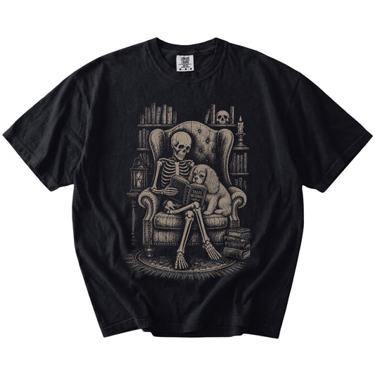 Skeleton reading in a library beside a Cavalier King Charles Spaniel on a Black Comfort Colors® T-shirt