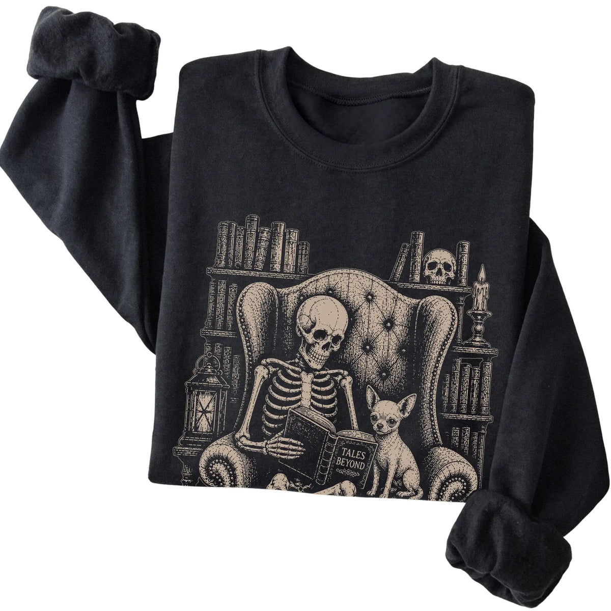 Folded Black sweatshirt with a skeleton reading Tales Beyond to a Chihuahua