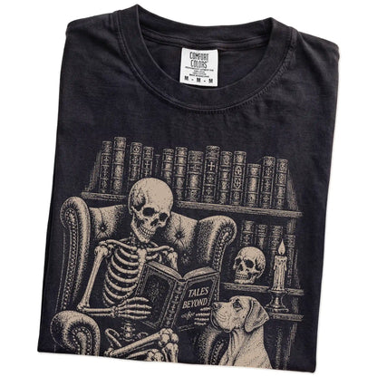 Folded Black Comfort Colors® T-shirt showing skeleton reading in a library beside a Great Dane
