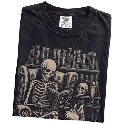 Folded Black Comfort Colors® T-shirt showing skeleton reading in a library beside a Husky
