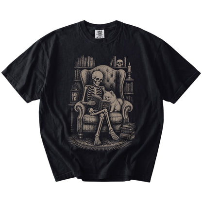 Skeleton reading in a library beside a Pomeranian on a Black Comfort Colors® T-shirt