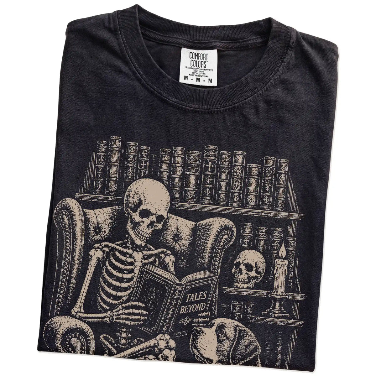Folded Black Comfort Colors® T-shirt showing skeleton reading in a library beside a Saint Bernard