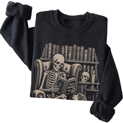 Folded Black sweatshirt with a skeleton reading Tales Beyond to a Springer Spaniel