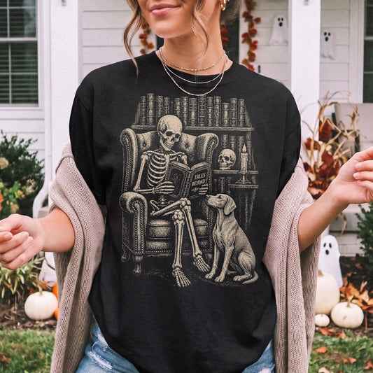 Model wearing a Black Comfort Colors® T-shirt showing skeleton reading in a library beside a Weimaraner