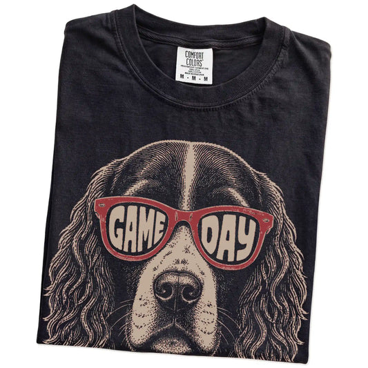 Folded Black Comfort Colors® T-shirt showing springer spaniel wearing red game day sunglasses