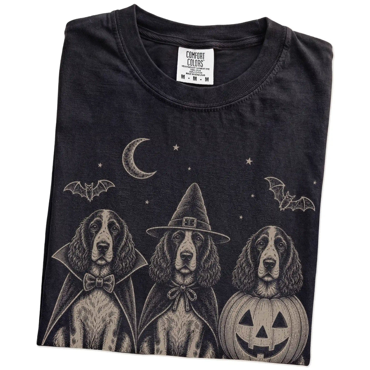 Folded Black Comfort Colors® T-shirt showing three Springer Spaniel dogs dressed for Halloween beneath bats and a crescent mo