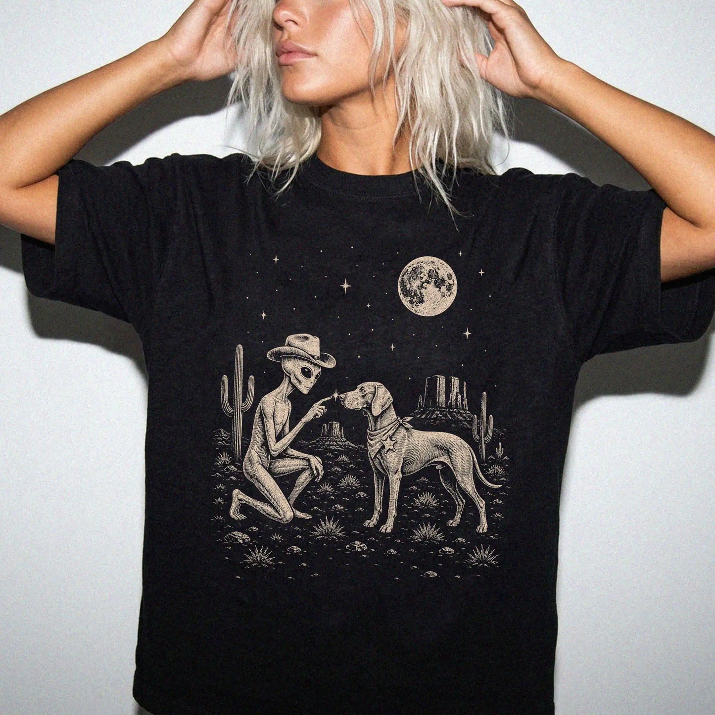 Model wearing a Black Comfort Colors® T-shirt with cowboy alien fist-bumping a weimaraner beneath the moon