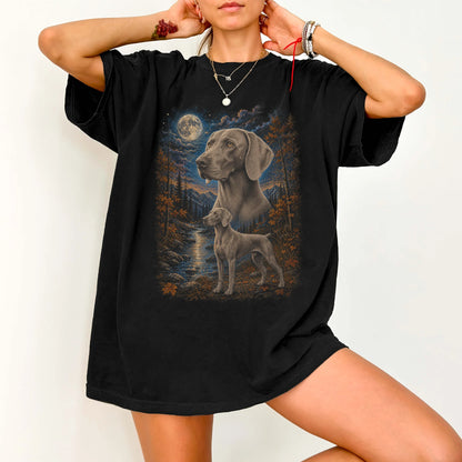 Model wearing a Black Comfort Colors® t-shirt featuring Weimaraner in a moonlit fall forest