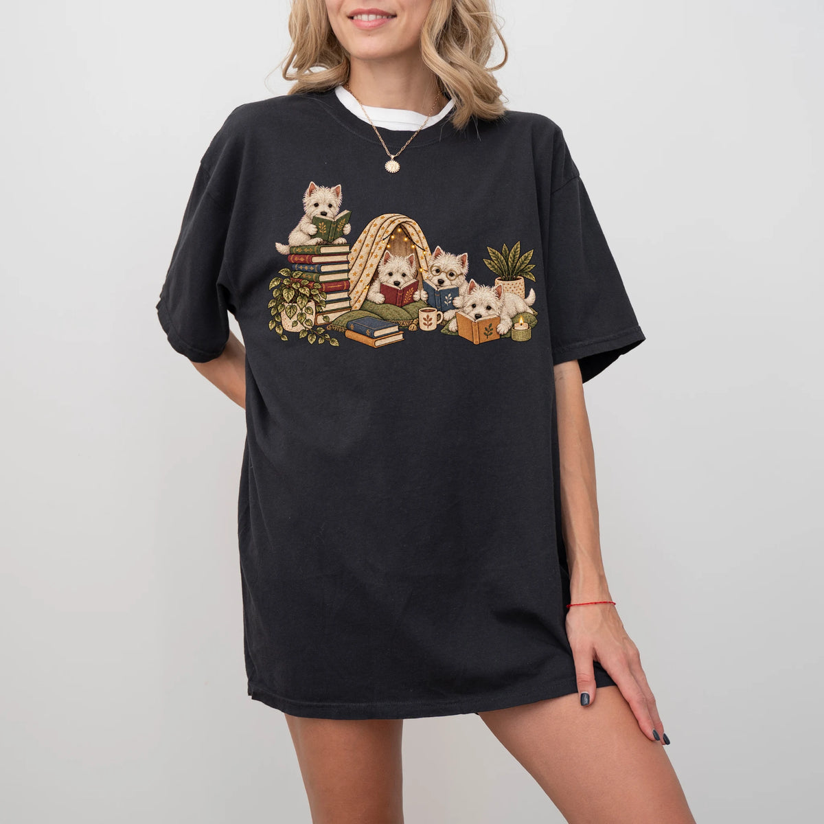 Westie puppies reading books in a cozy blanket fort on a Black T-shirt worn by a model