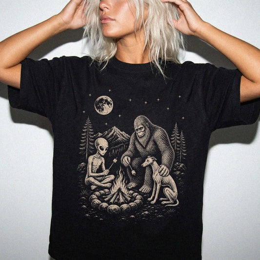 Model wearing a Black Comfort Colors® T-shirt showing Whippet camping with Bigfoot and an alien