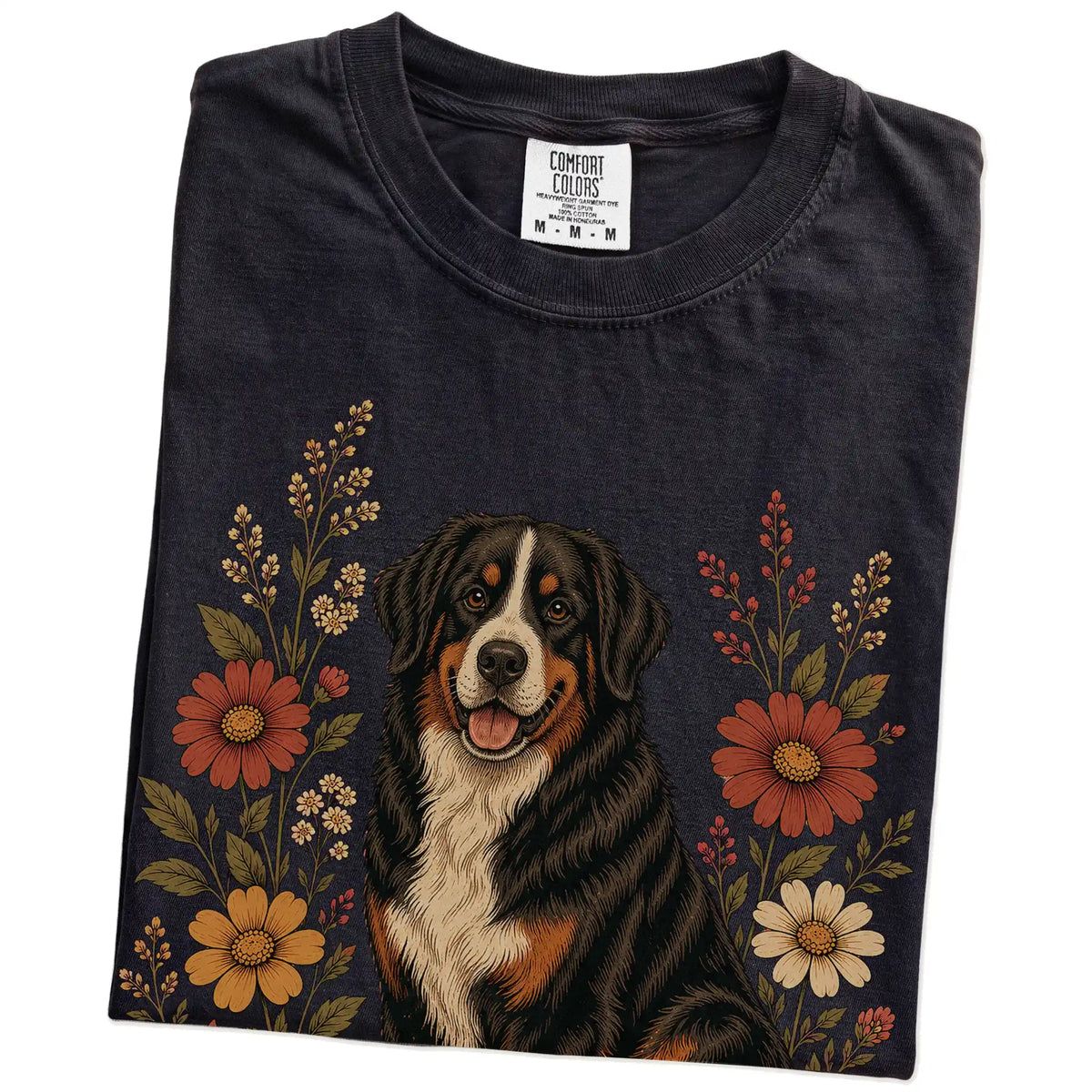 Folded Black Comfort Colors® T-shirt showing Bernese Mountain Dog portrait surrounded by wildflowers beneath the moon