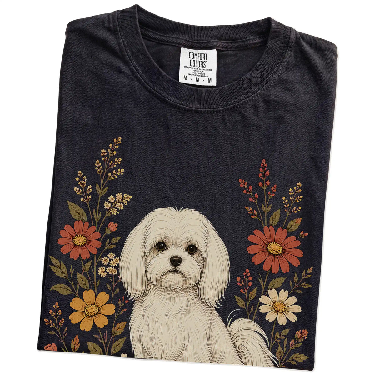 Folded Black Comfort Colors® T-shirt showing Maltese portrait surrounded by wildflowers beneath the moon