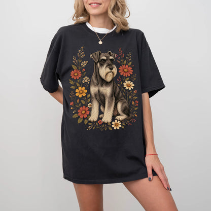 Model wearing a Black Comfort Colors® T-shirt showing Standard Schnauzer portrait surrounded by wildflowers beneath the moon