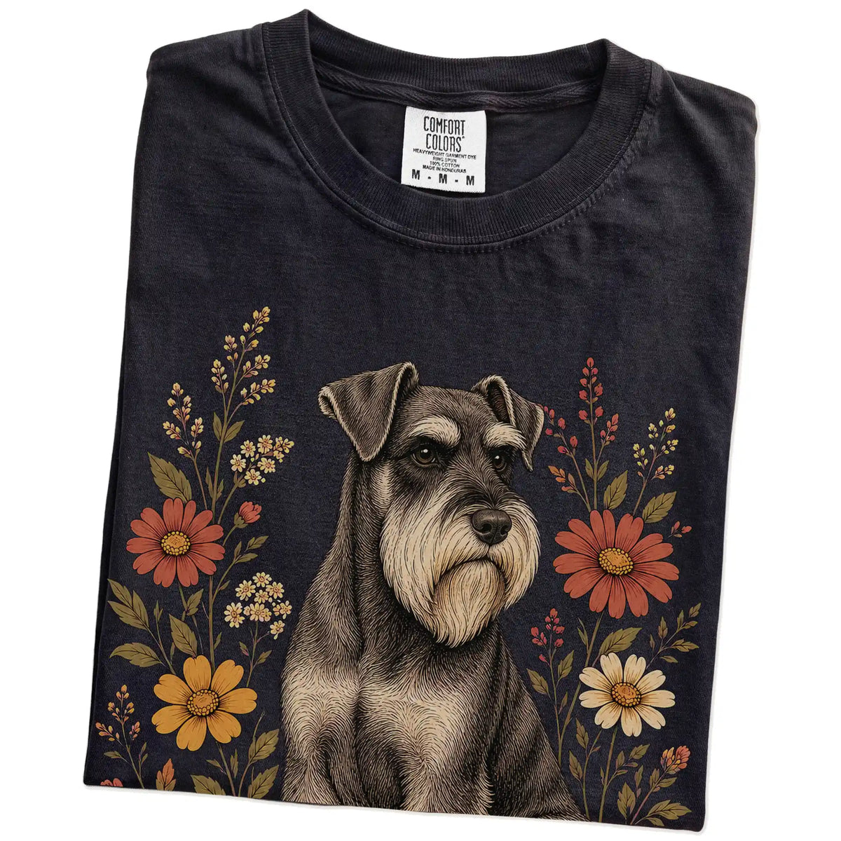 Folded Black Comfort Colors® T-shirt showing Standard Schnauzer portrait surrounded by wildflowers beneath the moon