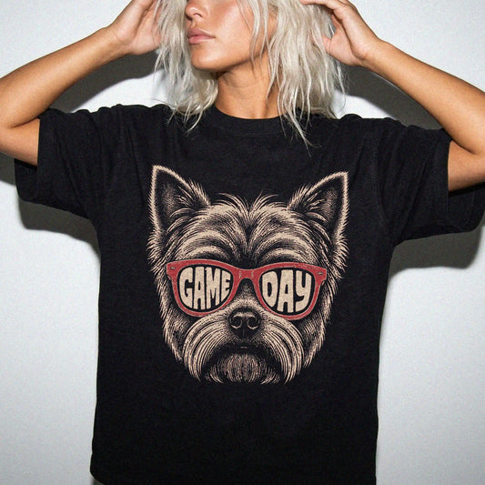 Model wearing a Black Comfort Colors® T-shirt with yorkie wearing red game day sunglasses