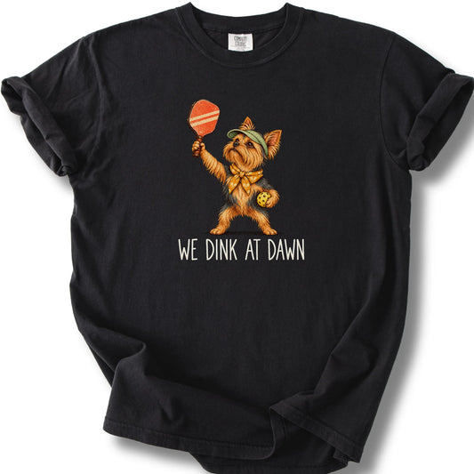 Yorkie with a pickleball paddle and ball on a Black Comfort Colors® T-shirt with We Dink at Dawn text