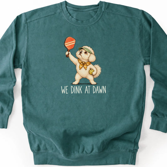 Bichon Frise with a pickleball paddle and ball on a Blue Spruce Comfort Colors® sweatshirt with We Dink at Dawn text