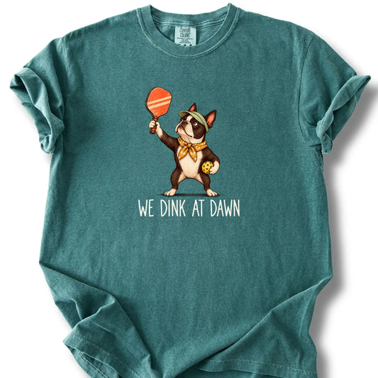 Boston Terrier with a pickleball paddle and ball on a Blue Spruce Comfort Colors® T-shirt with We Dink at Dawn text