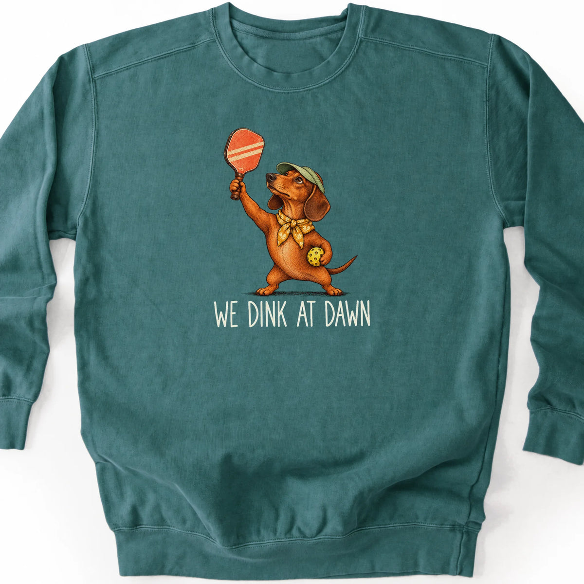 Dachshund with a pickleball paddle and ball on a Blue Spruce Comfort Colors® sweatshirt with We Dink at Dawn text