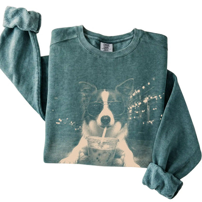 Border Collie wearing aviator sunglasses and drinking iced coffee on a Blue Spruce Comfort Colors 1566 Sweatshirt, folded view