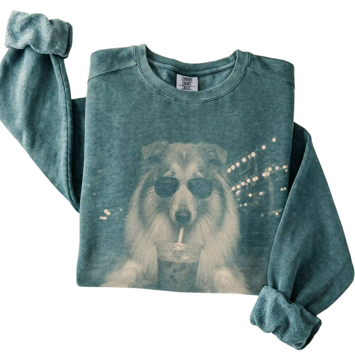 Collie wearing aviator sunglasses and drinking iced coffee on a Blue Spruce Comfort Colors 1566 Sweatshirt, folded view