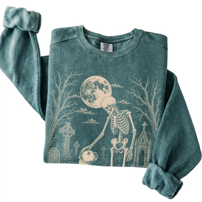 Folded Blue Spruce sweatshirt with a skeleton petting an American Bulldog in a graveyard