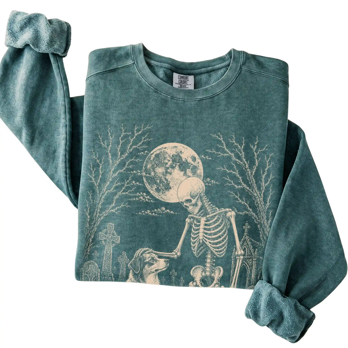 Folded Blue Spruce sweatshirt with a skeleton petting an Australian Shepherd in a graveyard