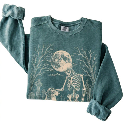 Folded Blue Spruce sweatshirt with a skeleton petting an Australian Shepherd in a graveyard