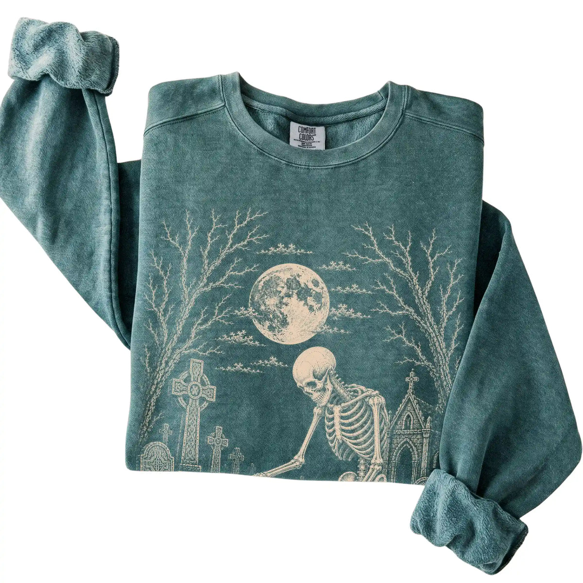 Folded Blue Spruce sweatshirt with a skeleton petting a Basset Hound in a graveyard