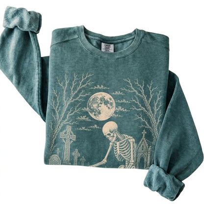 Folded Blue Spruce sweatshirt with a skeleton petting a Basset Hound in a graveyard